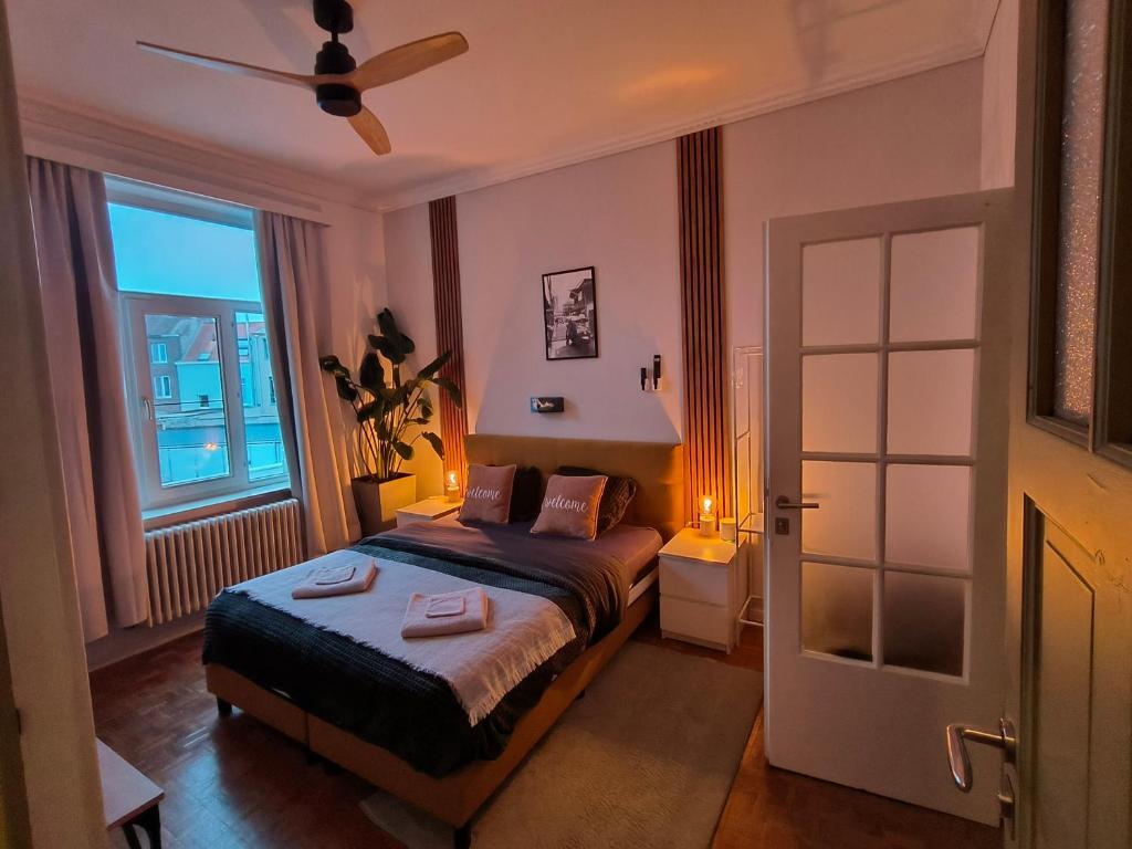 a bedroom with a bed with a ceiling fan and a window at 2Bangkok residence in Ghent