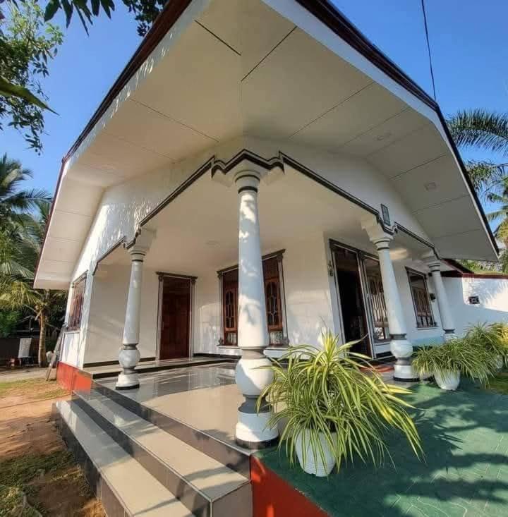 a white house with columns and plants in front of it at Lankadays in Negombo