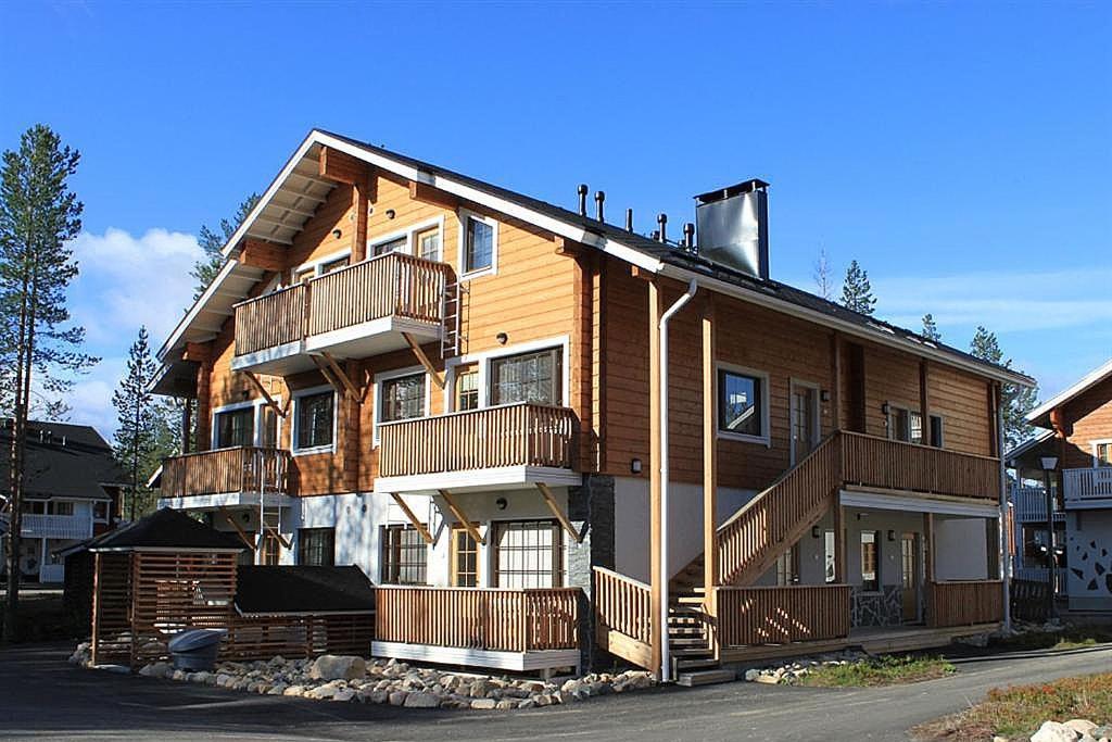 a large wooden building with balconies on a street at Cozy Alpine-Style Apartment in the Heart of Levi with Private Sauna & Fireplace in Levi