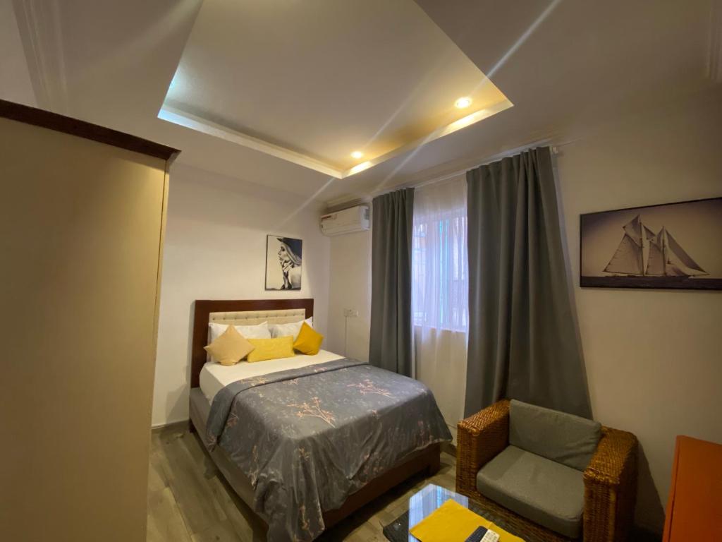 een slaapkamer met een bed, een stoel en een raam bij Trevors Home Place in Lagos
