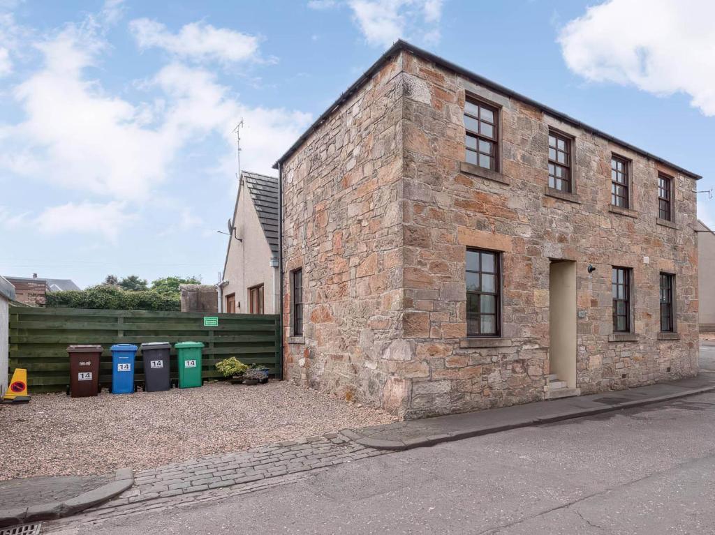 een bakstenen gebouw met vuilnisbakken ervoor bij The Howff in Anstruther