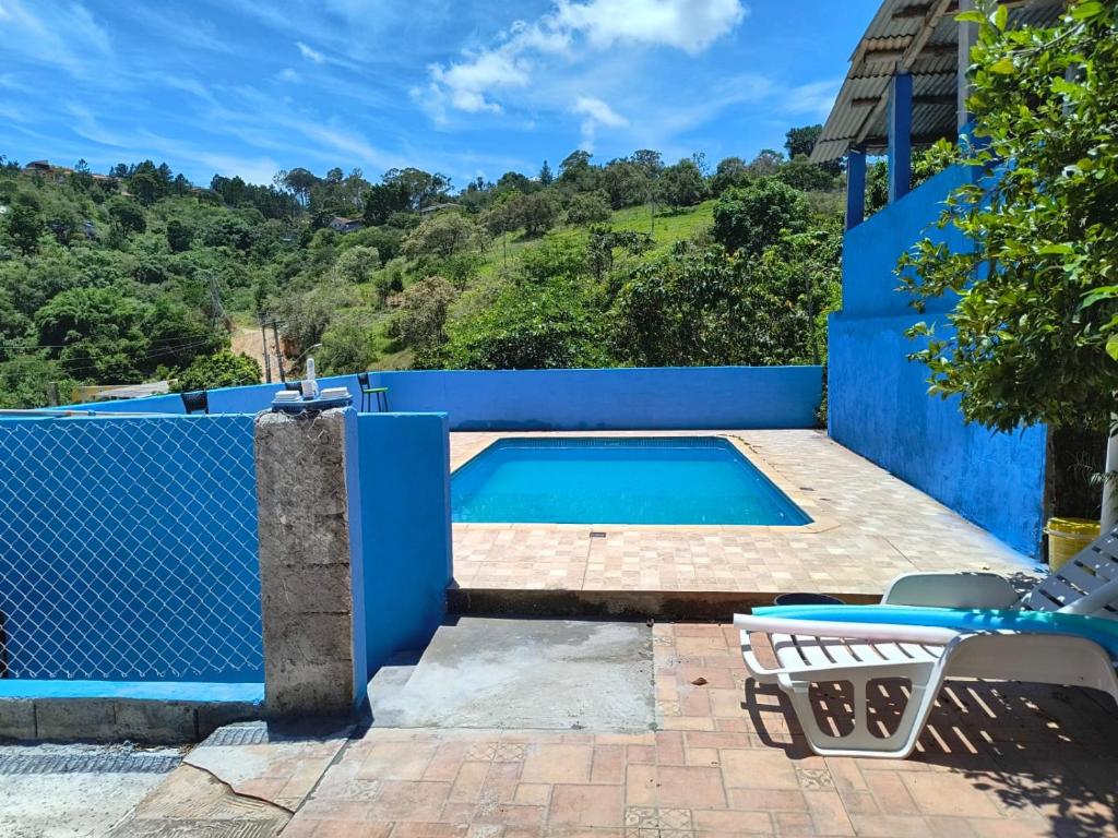 een zwembad met een blauw hek en een stoel bij CHÁCARA dos CHEIROS in Atibaia