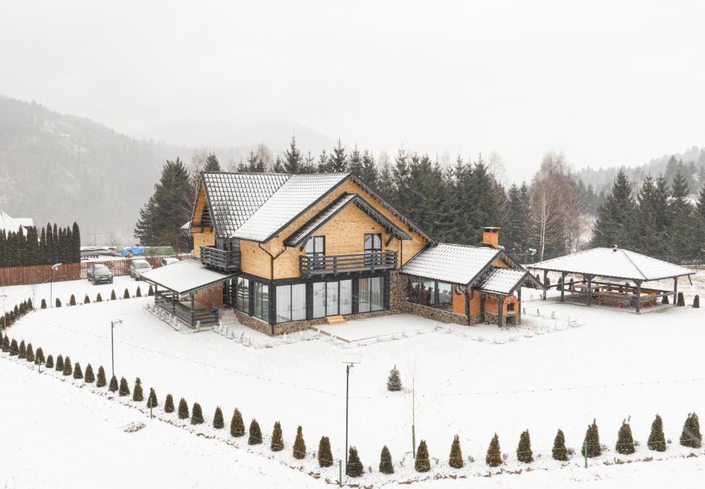 a house is covered in snow in a yard at Meștera 9 in Stînceni