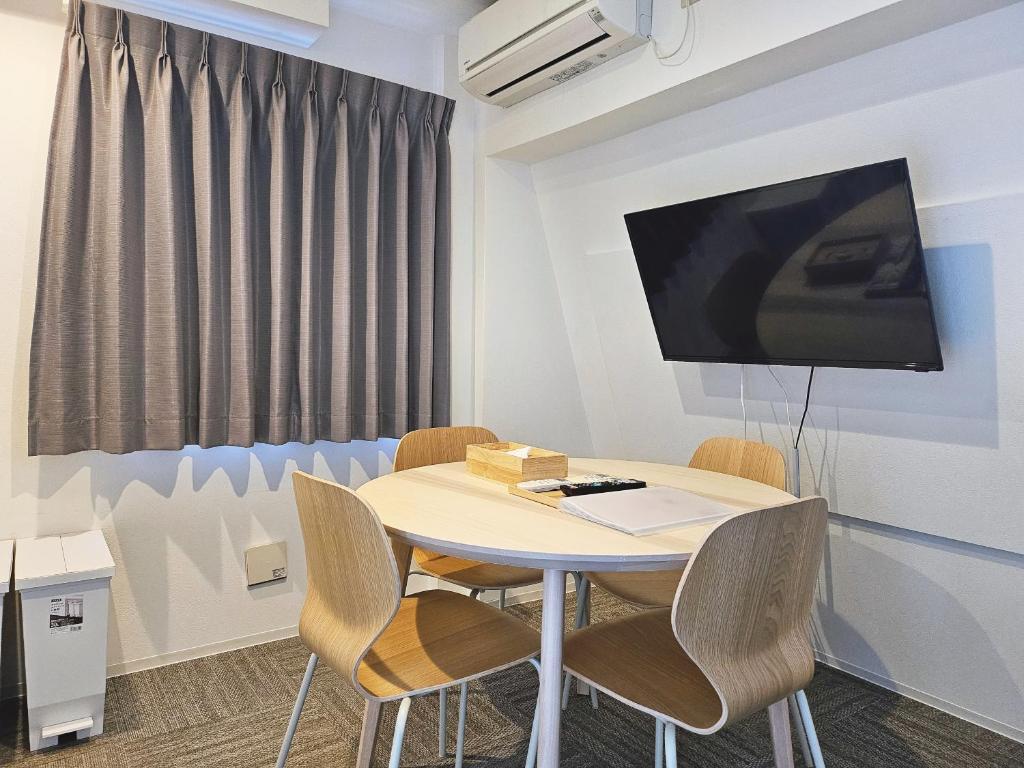 a room with a table with chairs and a tv on the wall at Hermitage Hotel Nishishin in Tokyo