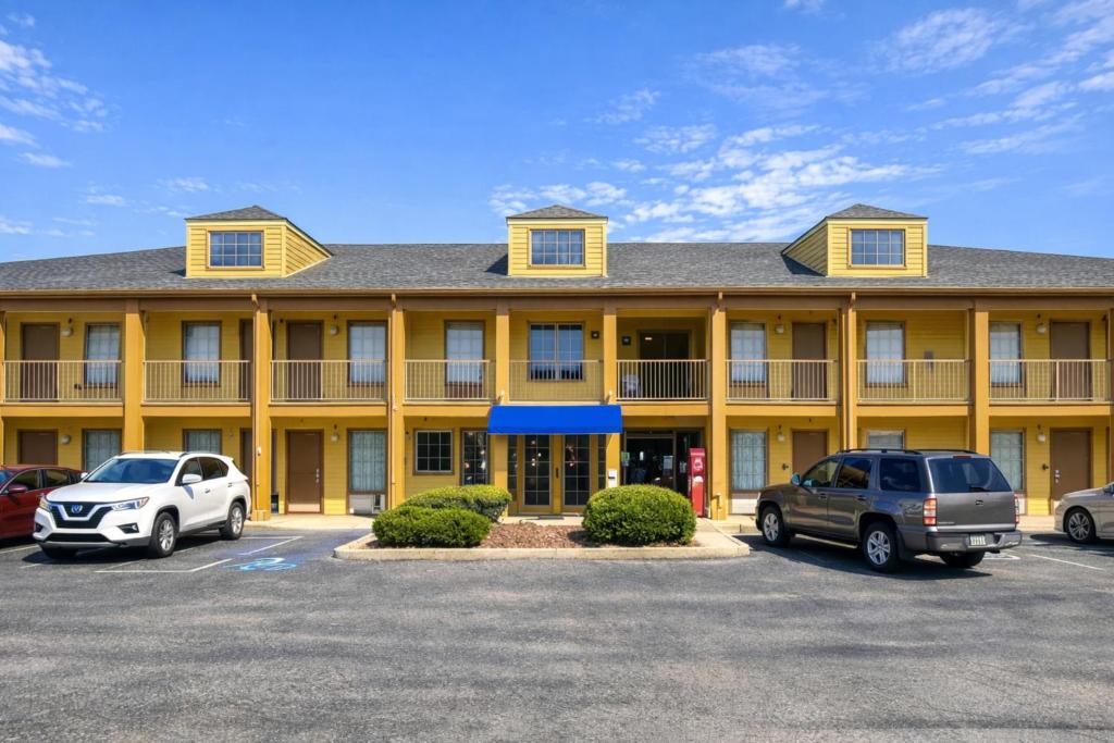 un grand bâtiment jaune avec des voitures garées dans un parking dans l'établissement Bonita Lakes Inn by Capital O Meridian I20, à Meridian