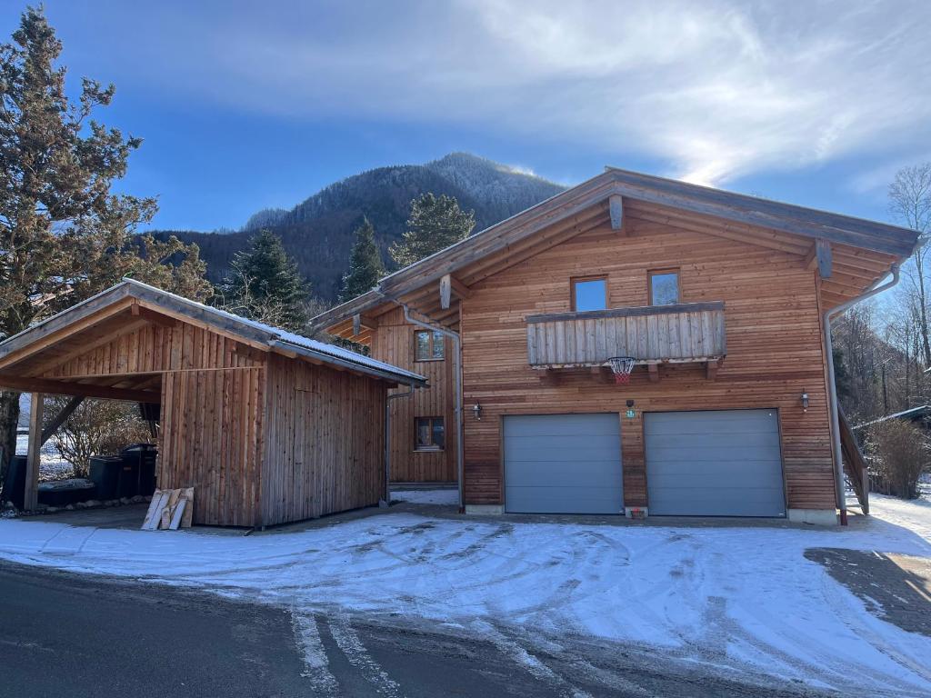 una casa di legno con due porte da garage nella neve di Ferienwohnung Waldzeit a Staudach-Egerndach