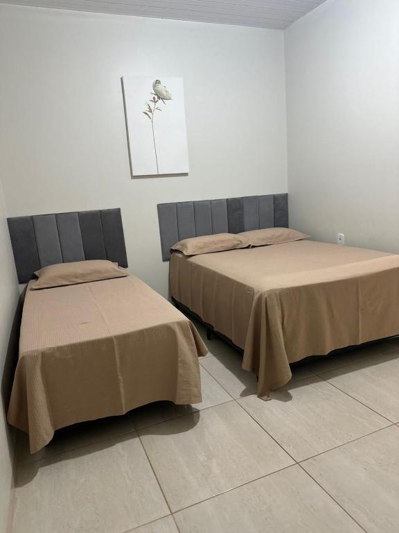 two beds sitting next to each other in a room at Suíte com ar, frigobar atende até 3 pessoas não a estacionamento in Sinop