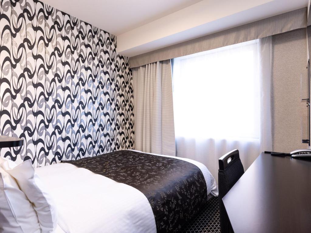 a hotel room with a bed and a window at APA Hotel Fukui Katamachi in Fukui
