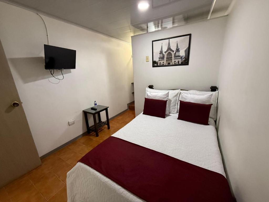 een slaapkamer met een bed en een flatscreen-tv bij Ayenda Marana in Manizales