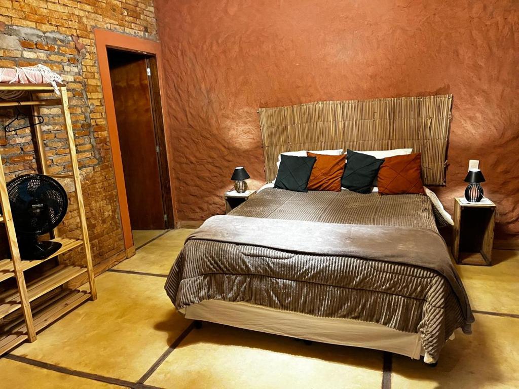 une chambre avec un lit et un mur de briques dans l'établissement Sítio Santo Antônio - Chalé com Ofurô, à Atibaia