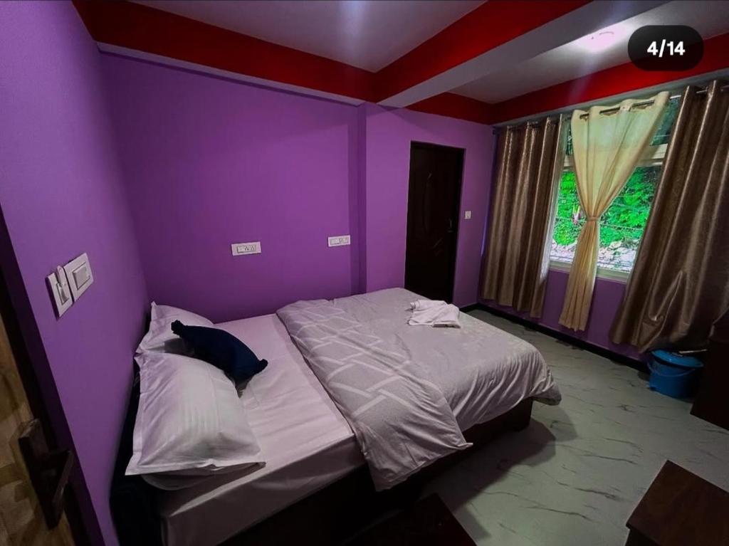 a bedroom with purple walls and a bed at Tashidelk homestay in Darjeeling