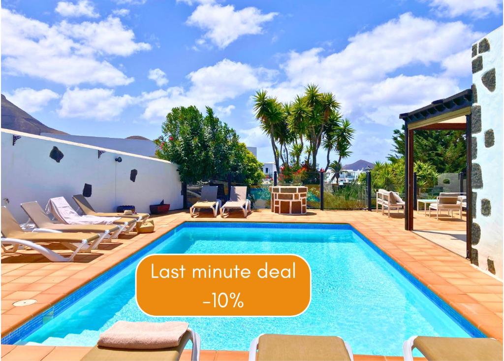 een zwembad in een tuin met een huis bij Spacious Private Villa up to 16 - Authentic Yaiza - Volcano, Timanfaya park, Bodega & South Beaches - Heated Pool - Game Room - Charcoal grill in Yaiza