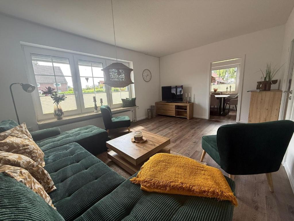 a living room with a green couch and a table at Huus Christine in Holtgast