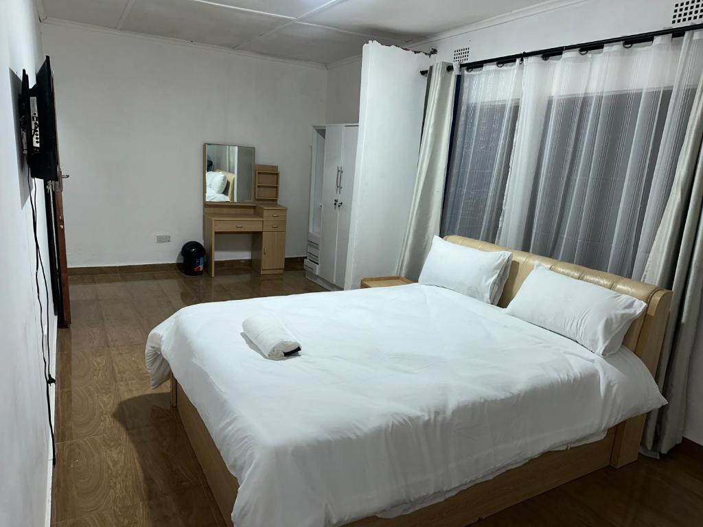 een groot wit bed in een kamer met een raam bij The 12th Avenue in Lusaka