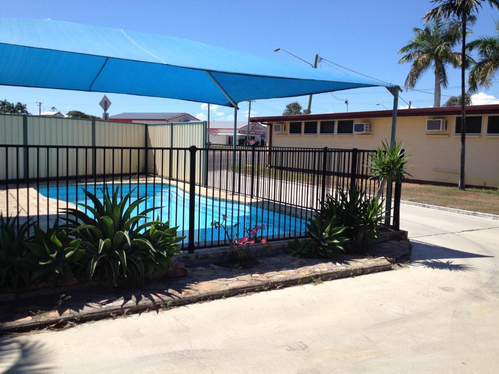 a fence around a swimming pool with a blue umbrella at Shell Motel (Pearly Shell Motel) in Bowen
