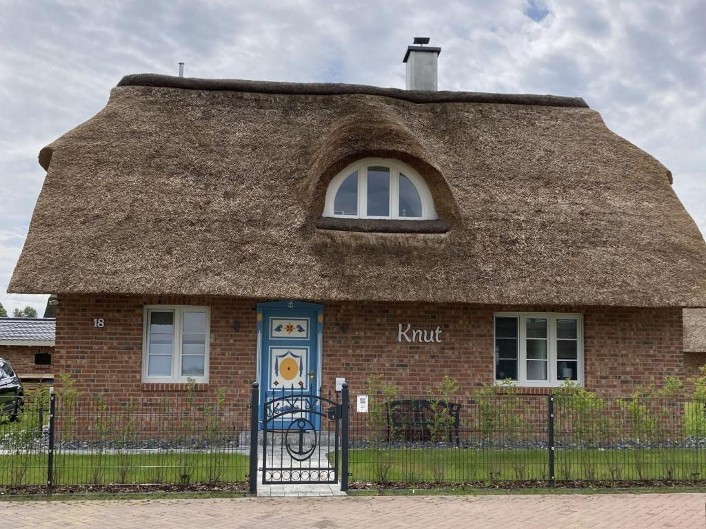 a thatch roofed house with a fence in front of it at Holiday Home Knut by Interhome in Mellnitz
