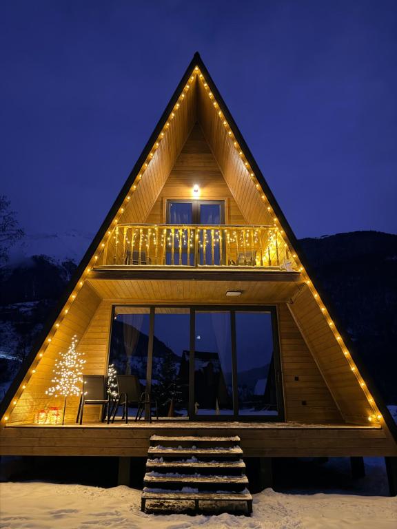 een houten huis met lampjes erop in de sneeuw bij WinterFell Mestia in Mestia