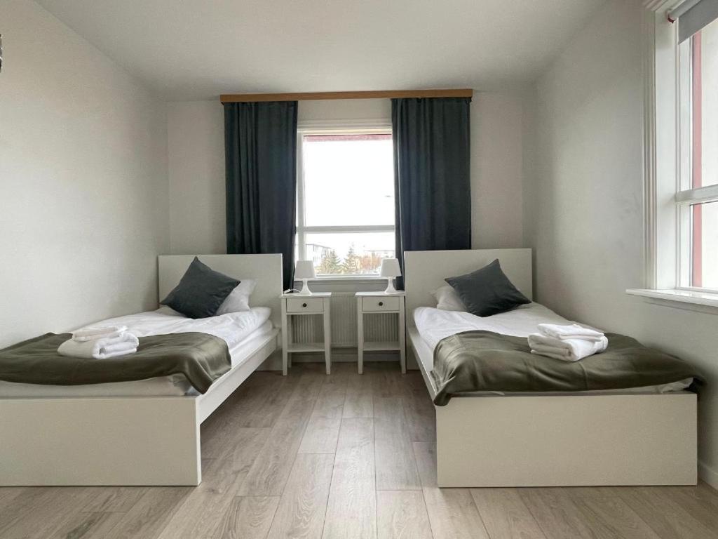 two beds in a room with a window at IQ apartments 3 in Ytri-Njarðvík