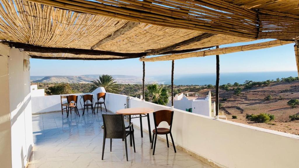 a balcony with chairs and tables on a roof at Taghazout surf in Tamraght Ouzdar