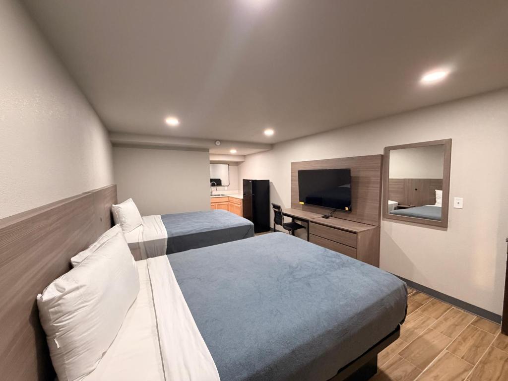 una camera d'albergo con due letti e una TV a schermo piatto di Economy Suites Fort Smith a Fort Smith