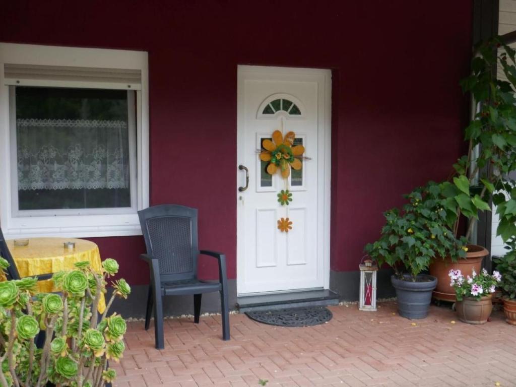 a red house with a chair and a white door at Apartment Im Hof by Interhome in Pittenbach