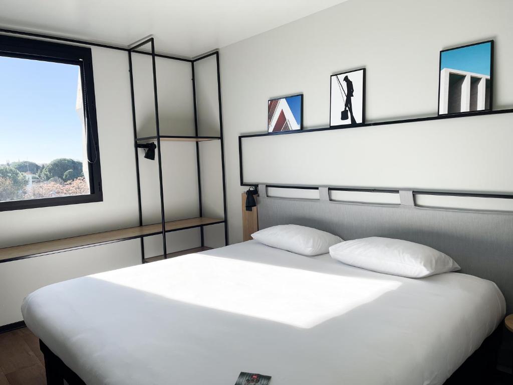 een slaapkamer met een wit bed en een raam bij Ibis Lunel Petite Camargue in Lunel