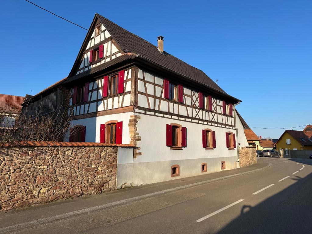 a white building with red shutters on a street at Loft à colombages "1789" - 80m2 in Innenheim