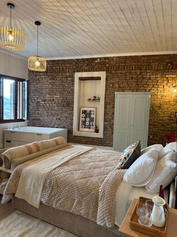 a bedroom with a large bed and a brick wall at Aprosmeno House 7 in Agros