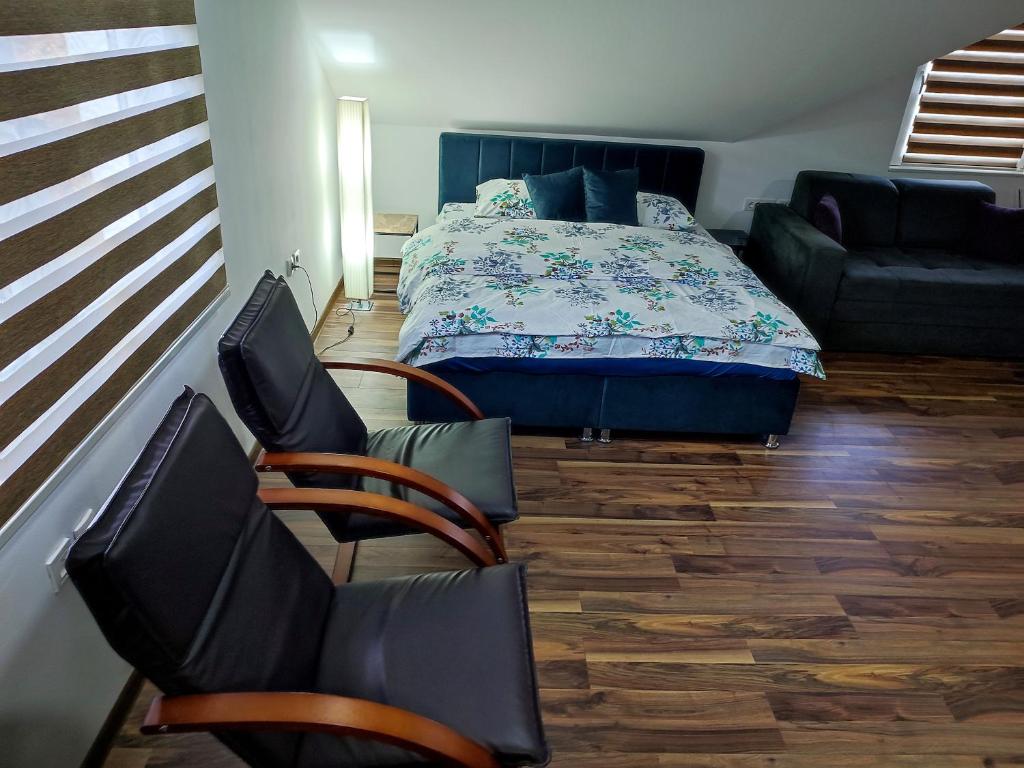 a bedroom with a bed and two chairs and a couch at New Modern Duplex with Free Parking in Prijepolje