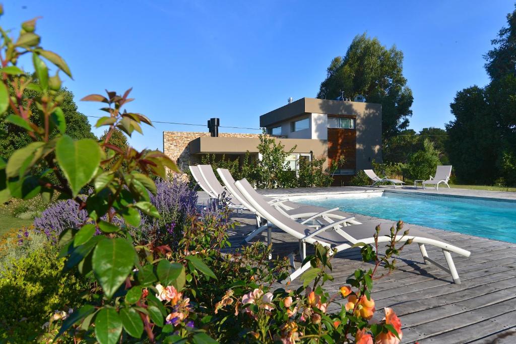 a group of white lounge chairs next to a swimming pool at Samay Huasi - Cabañas y Casa de Te in Chapadmalal