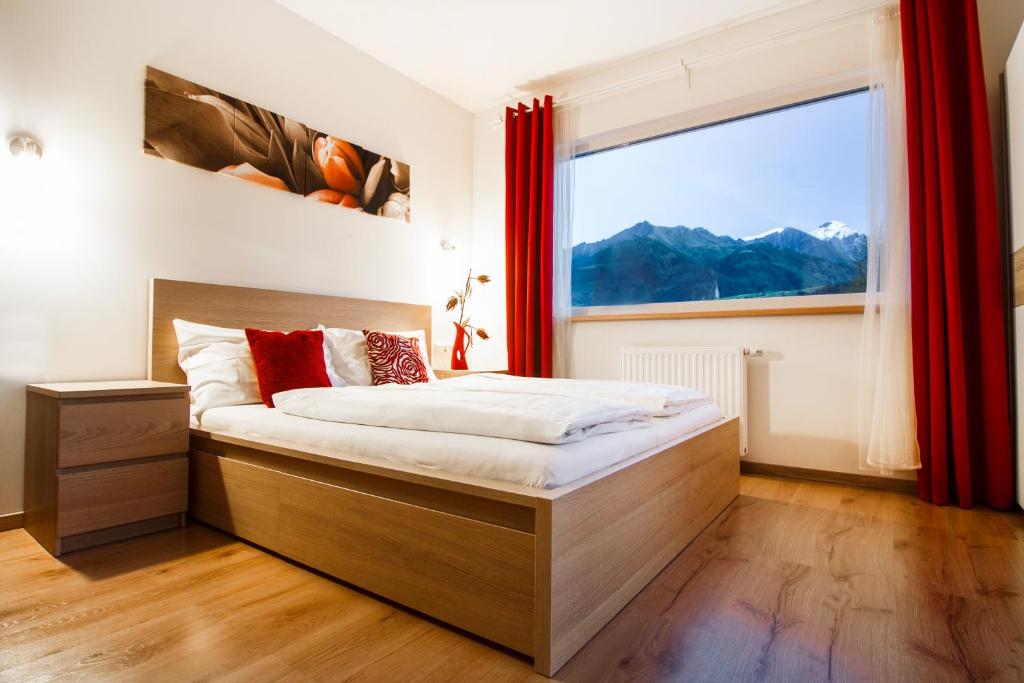 Schlafzimmer mit einem Bett und einem großen Fenster in der Unterkunft Oscar & Sons Apartments in Piesendorf