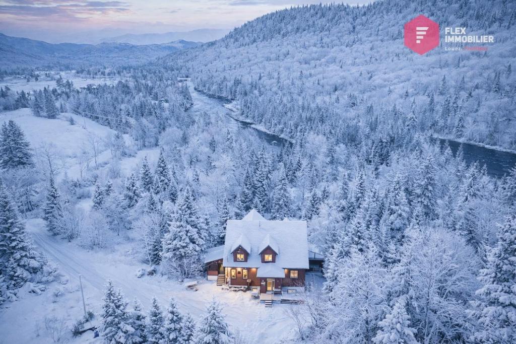 een huis midden in een met sneeuw bedekt bos bij Stoneham's St-Évasion - 25 min from Qc, SPA for 9 in Stoneham