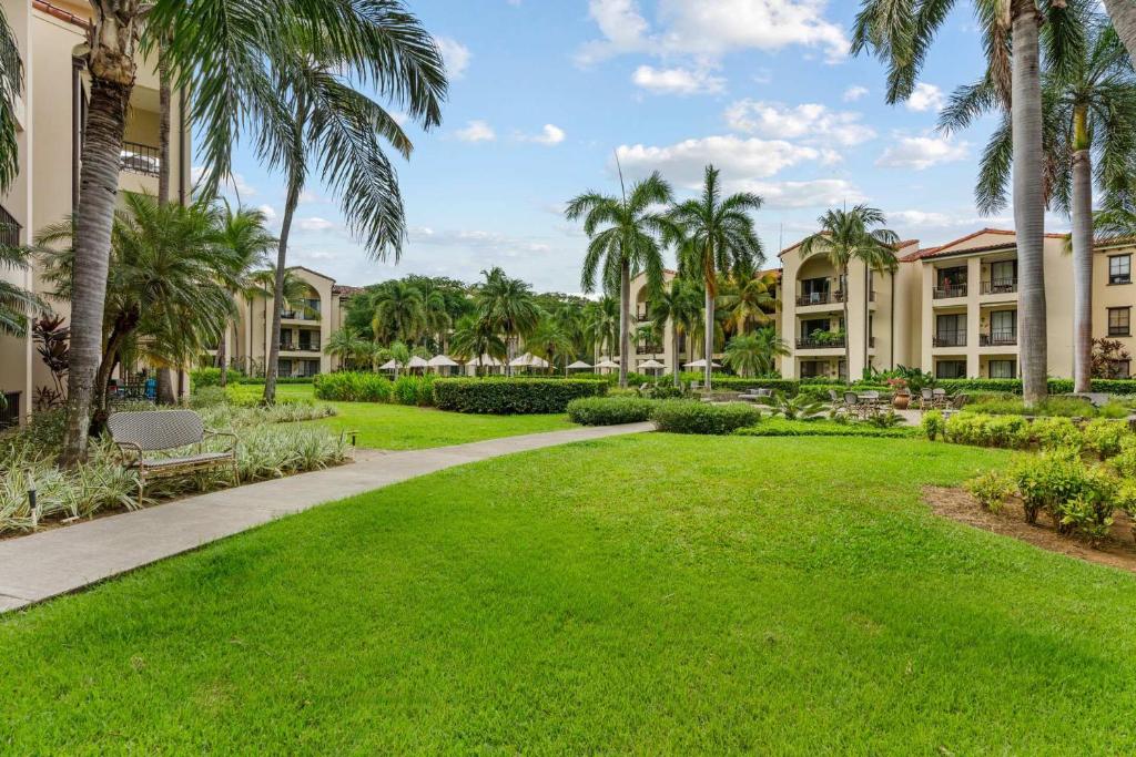 a walkway through a park with palm trees and condos at Elegant Condo in High-End Resort Community with Pool and Beach Club Access in Coco