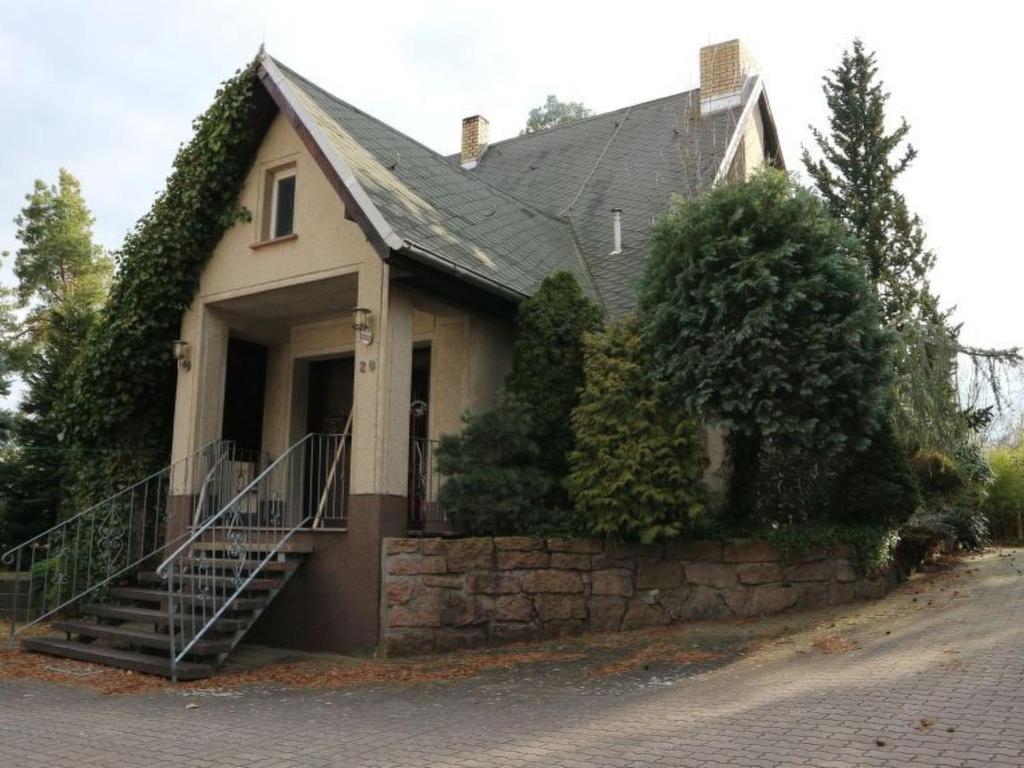 a house with a porch and a stone wall at Apartment mit Pool by Interhome in Bad Schmiedeberg