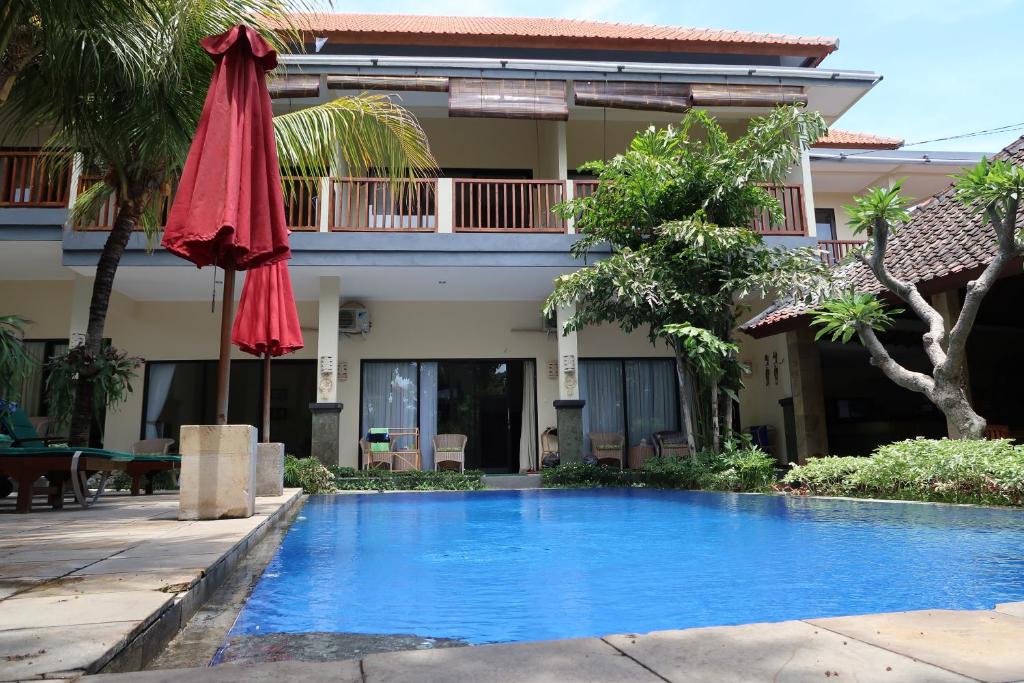 einem Pool mit einem roten Regenschirm und einem Gebäude in der Unterkunft Bali Reef Divers Tulamben in Tulamben