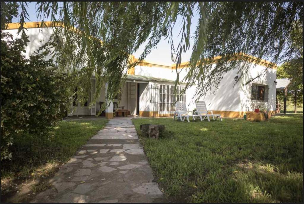 een huis met twee stoelen en een pad in de tuin bij La Cuadra - Puesto de Campo Argentino in Lobos