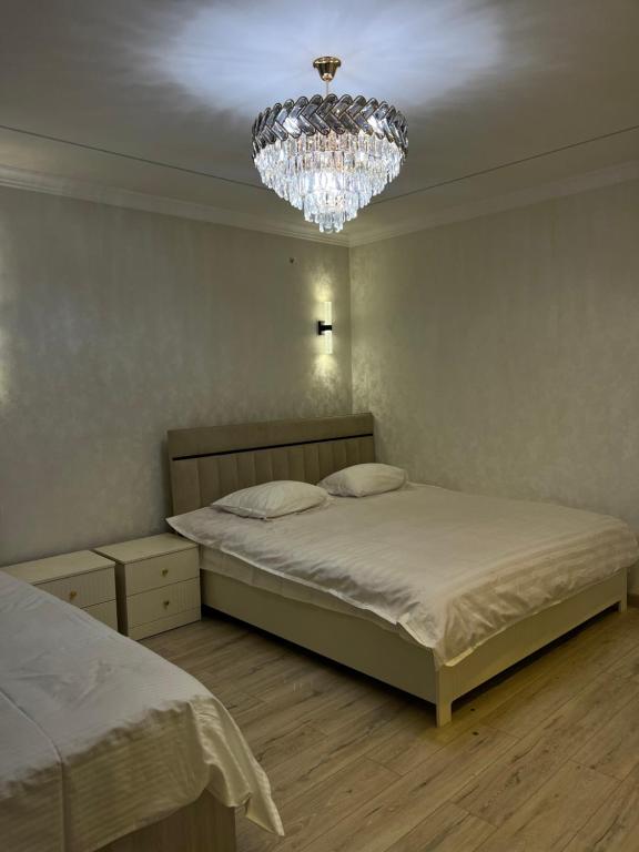 een slaapkamer met 2 bedden en een kroonluchter bij Royal in Osh