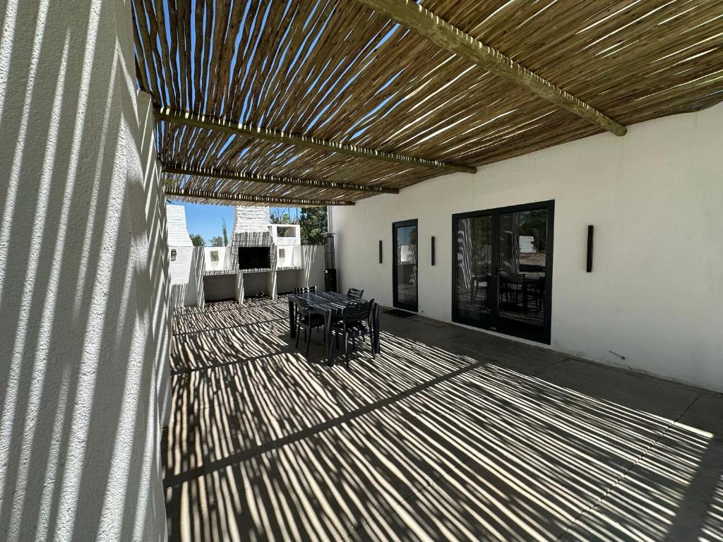 a patio with a table and a wooden ceiling at White House Cottage in Koekoeb