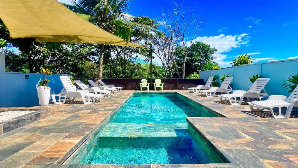 a swimming pool with chairs and an umbrella at Ruta Verde BB in Tambor