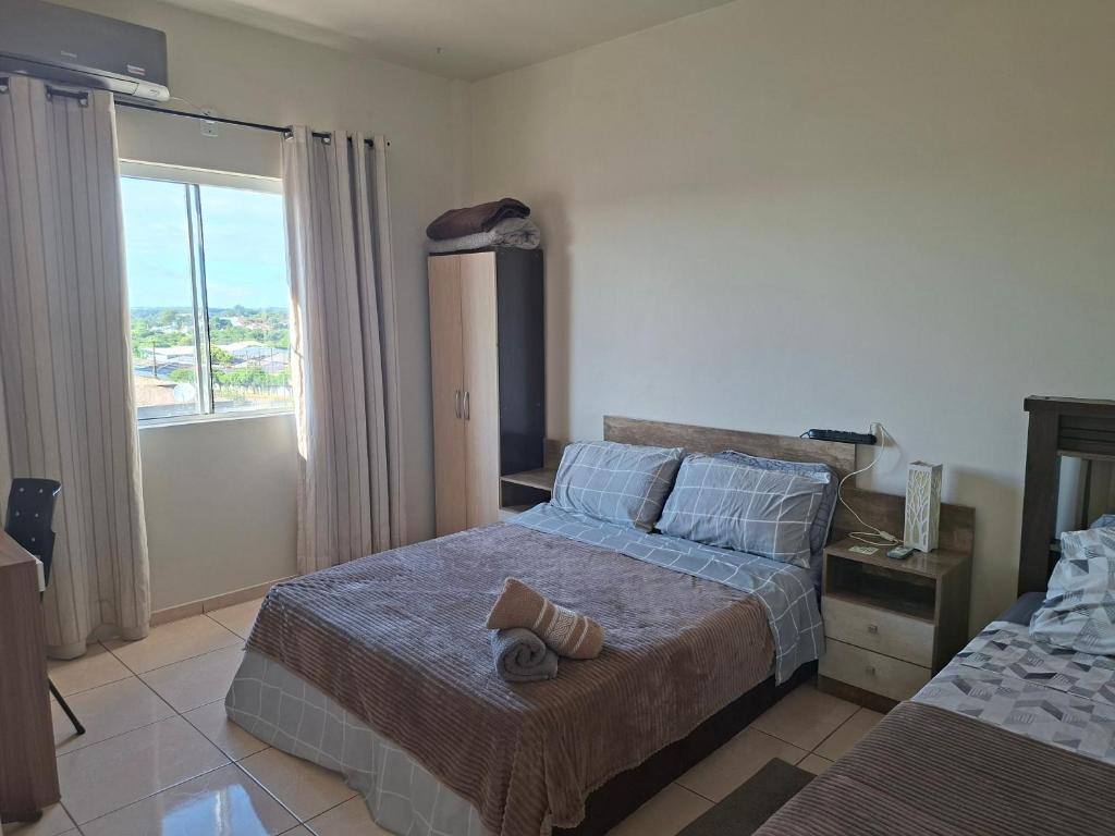 een slaapkamer met een bed met een paar schoenen erop bij Apart próximo a Unimed, Catedral, HSA com 2 Ar e garagem in Santo Ângelo