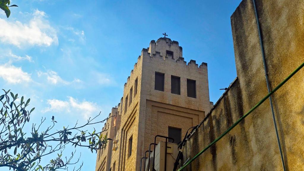 een hoog bakstenen gebouw met een kruis bovenop bij St Thomas Guesthouse - Jerusalem in Jeruzalem