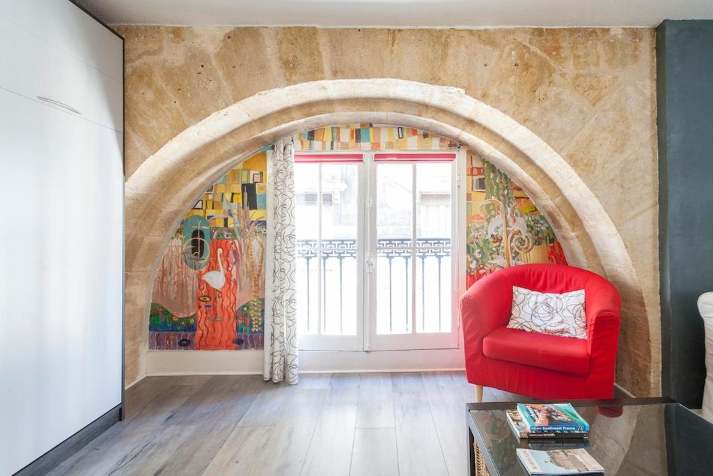 a living room with a red chair and a mural at Studio Alienor Place la Bourse Bordeaux in Bordeaux