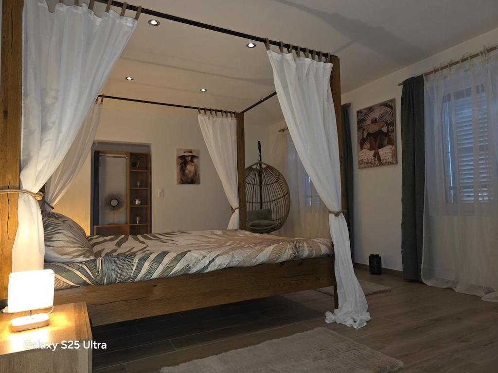a bedroom with a canopy bed with white curtains at Appartement de Charme in Bévilard