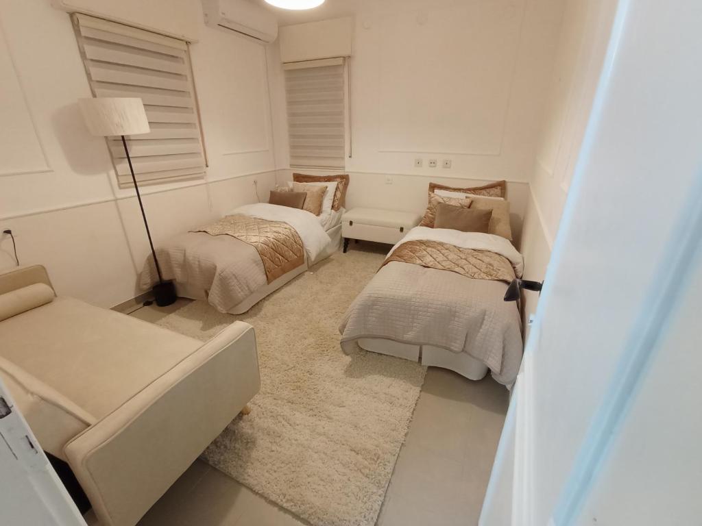 ein weißes Zimmer mit 2 Betten und einem Sofa in der Unterkunft דירת נופש צימר אירוח בצפת צפון קרוב למקווה ורשבי in Safed