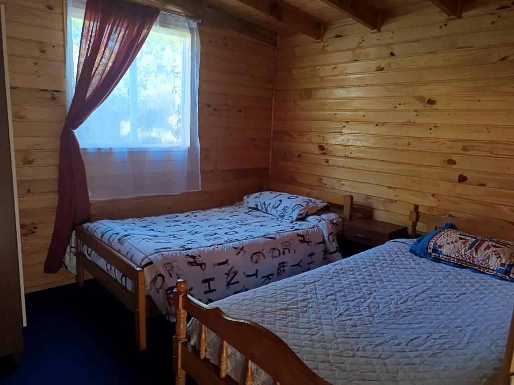 due letti in una baita con finestra di Refugio Lemuy - Chiloé a Puqueldón