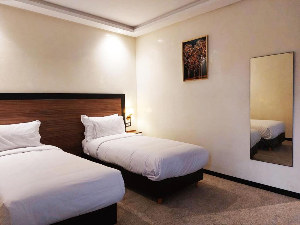 a hotel room with two beds and a mirror at Hotel redouane in Marrakech