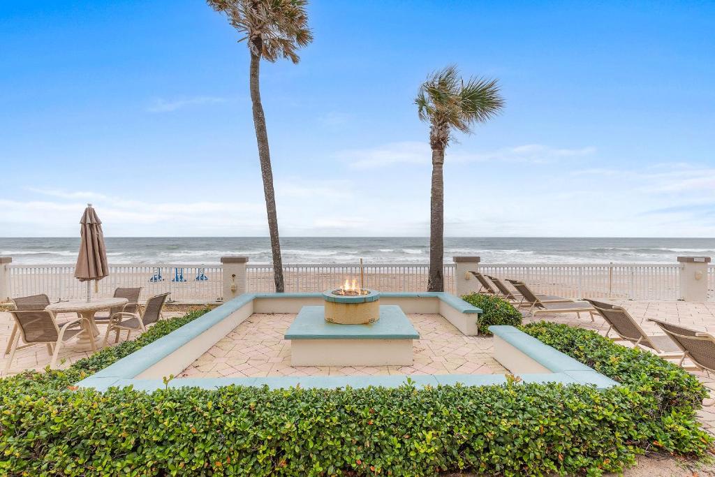 a patio with chairs and palm trees and the beach at Daytona Beach Resort 1004 in Daytona Beach