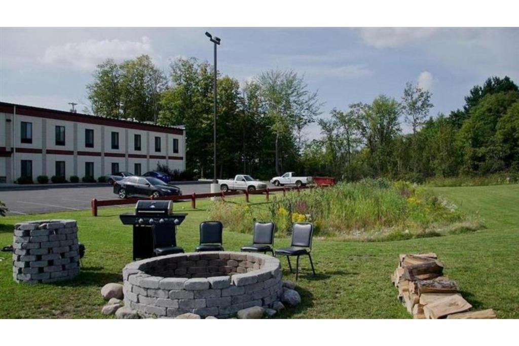 een groep stoelen rond een vuurplaats bij Pleasant Night Inn Watertown by Hotel O in West Carthage