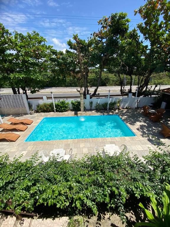 a swimming pool in a yard with chairs and trees at Pousada Rota Beach in Porto De Galinhas