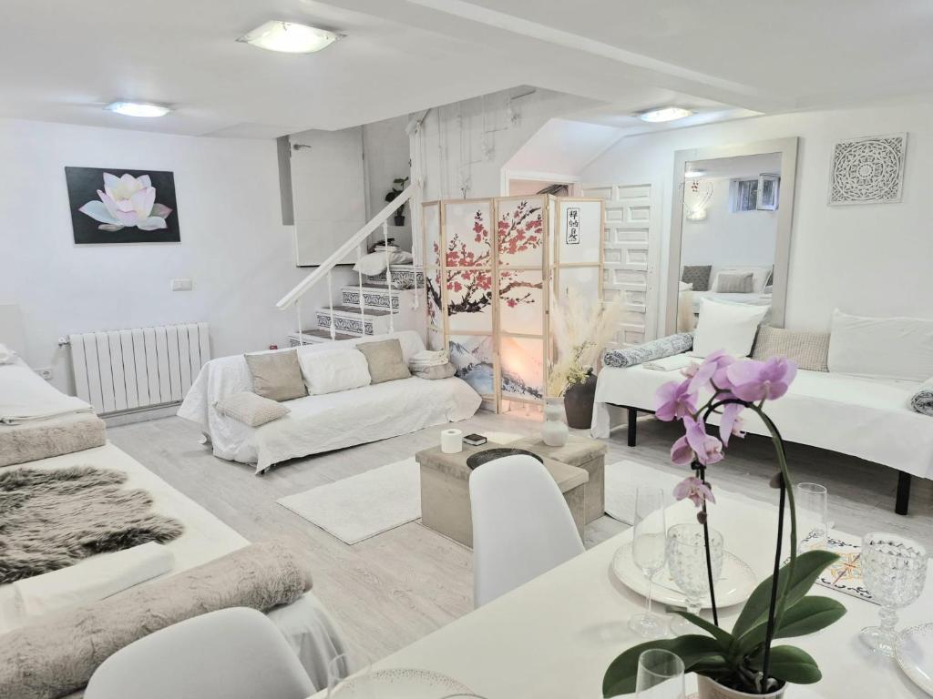 een witte woonkamer met witte meubels en paarse bloemen bij Basement studio in hosts house with private terrace and BBQ Ideal for The camino in Zizur Mayor